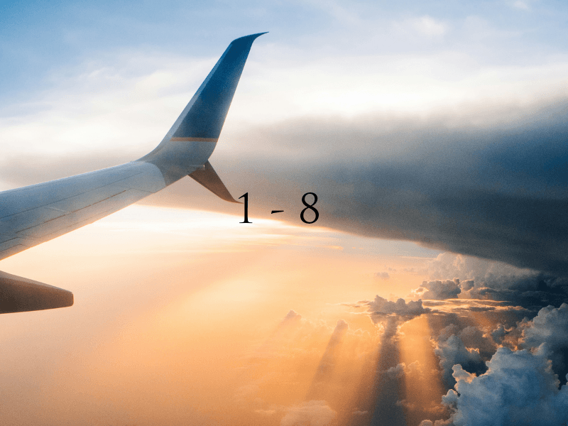 Airplane wing above clouds during sunset, with warm colors illuminating the sky.