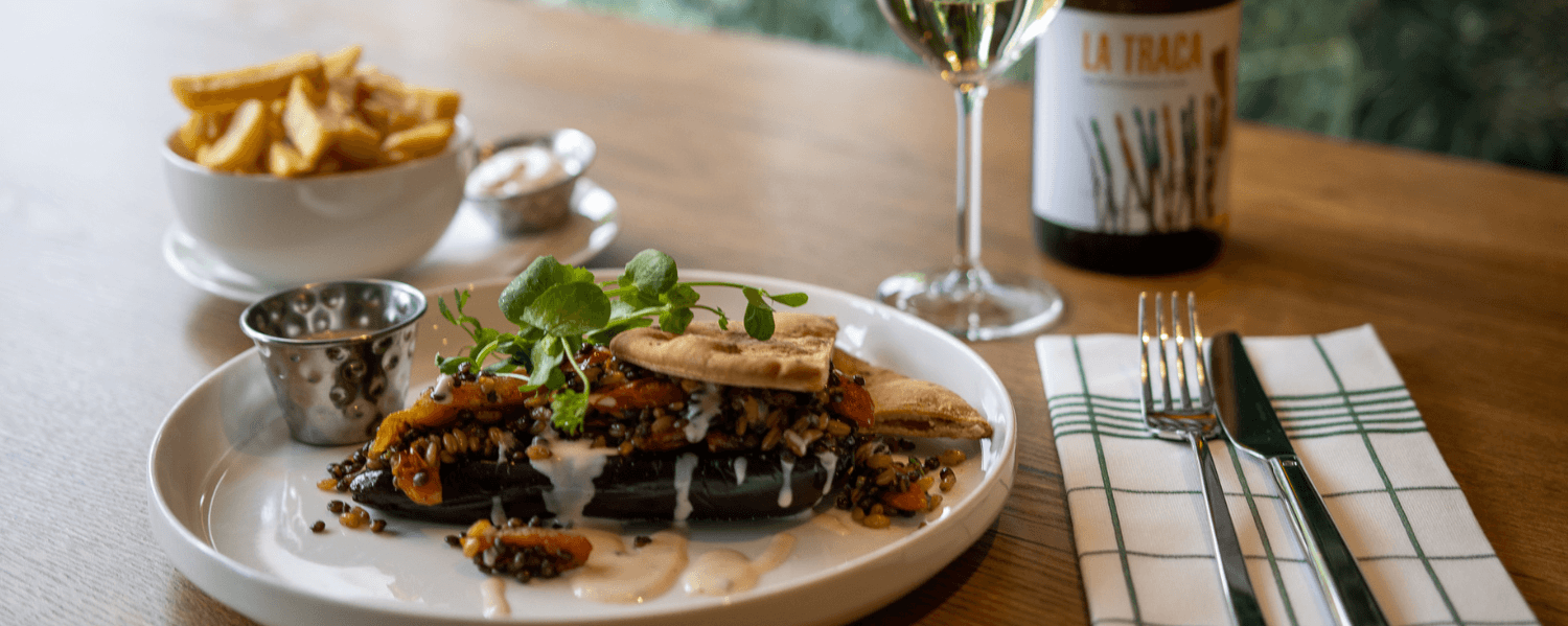 A plate with delicious food and a glass of wine on a table.