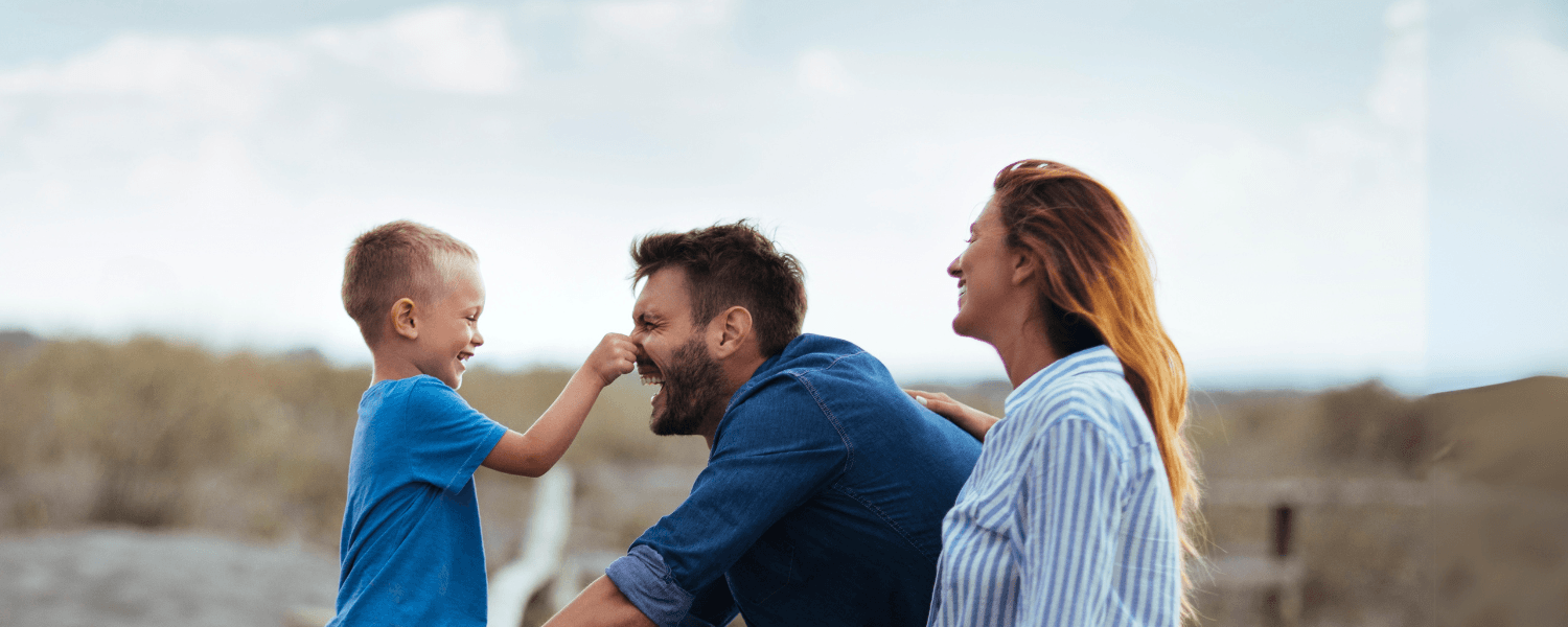 Laughing family with father, mother, and child having fun together in nature.