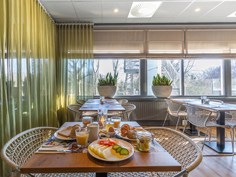 Breakfast at Amrâth Airport Hotel Rotterdam with fresh bread, cheese, cucumber, tomato, and a delicious glass of orange juice