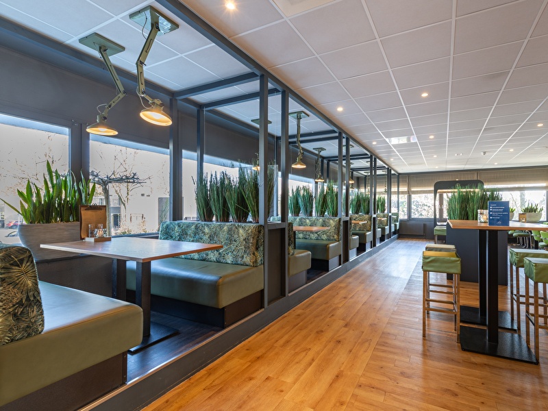 Green colored restaurant with benches and tables in Amrâth Airport Hotel Rotterdam